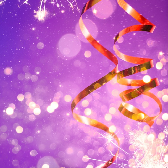 Luftschlangen und Wunderkerzen auf lilafarbenem Hintergrund.